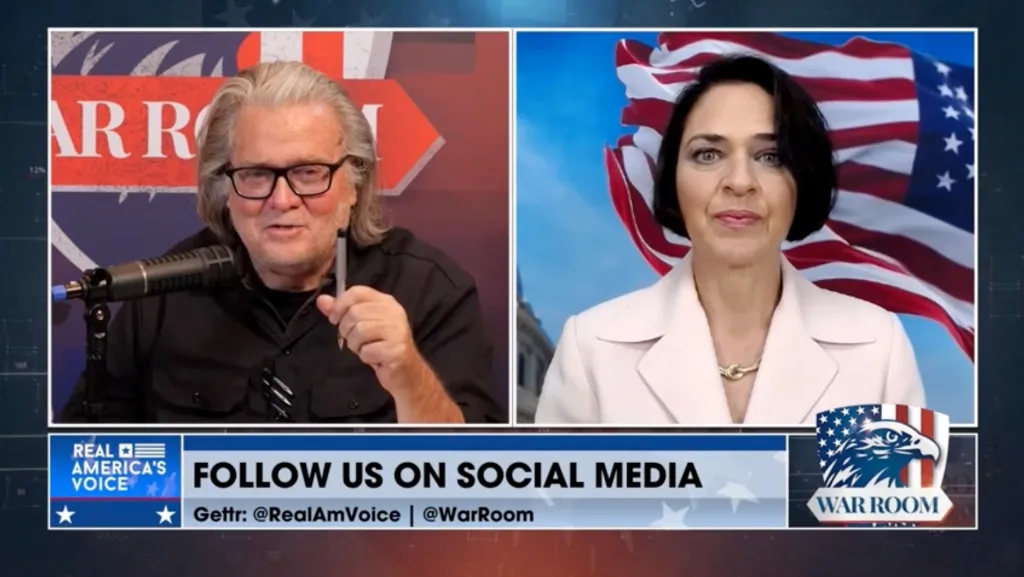 A screenshot of a political streaming show that shows a split screen of two people talking to one another. The screenshot includes lower-third graphic that reads in part, "Real America's Voice" and "Follow us on Social Media."