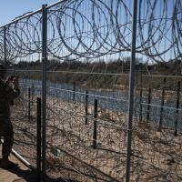 A U.S. Army soldier standing at a razor-wire-topped fence monitors the border with Mexico in Eagle Pass, Texas.