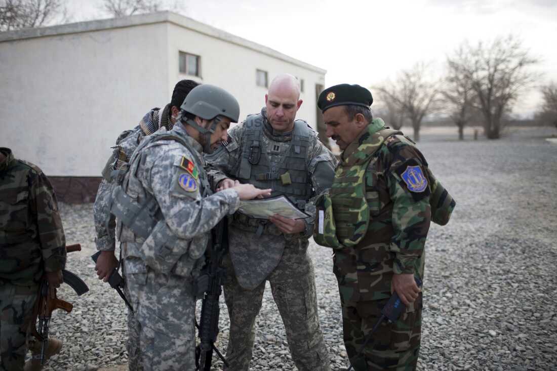 A U.S. Air Force captain goes over the day's mission route map with an Afghan National Army officer with assistance from an Afghan interpreter (left), before the U.S.-Afghan convoy sets off in Ghazni, Afghanistan, on March 16, 2009.